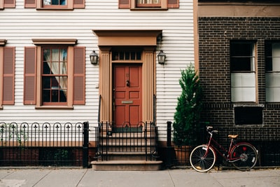 红色自行车停在黑色金属门在房子前面
